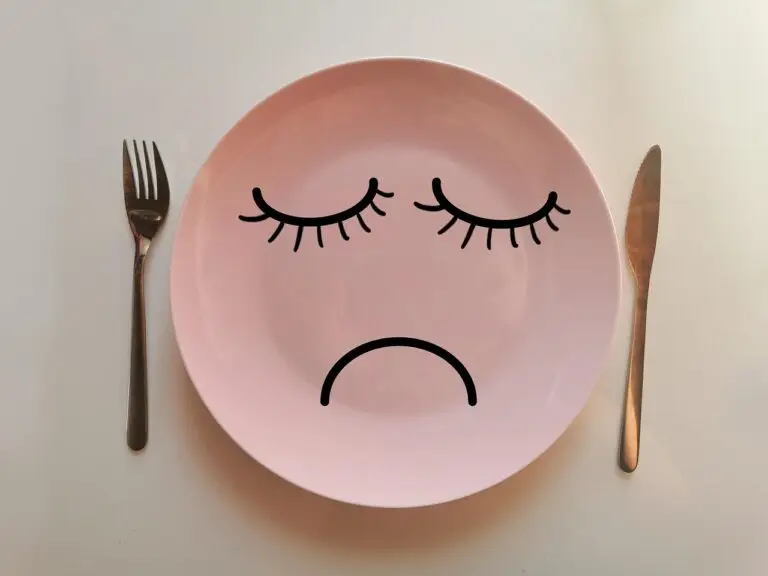 assiette rose avec une bouche et des yeux, posée sur une table accompagnée d'une fourchette et d'un couteau. Les bienfaits de l'hypnose dans une perte de poids durable.