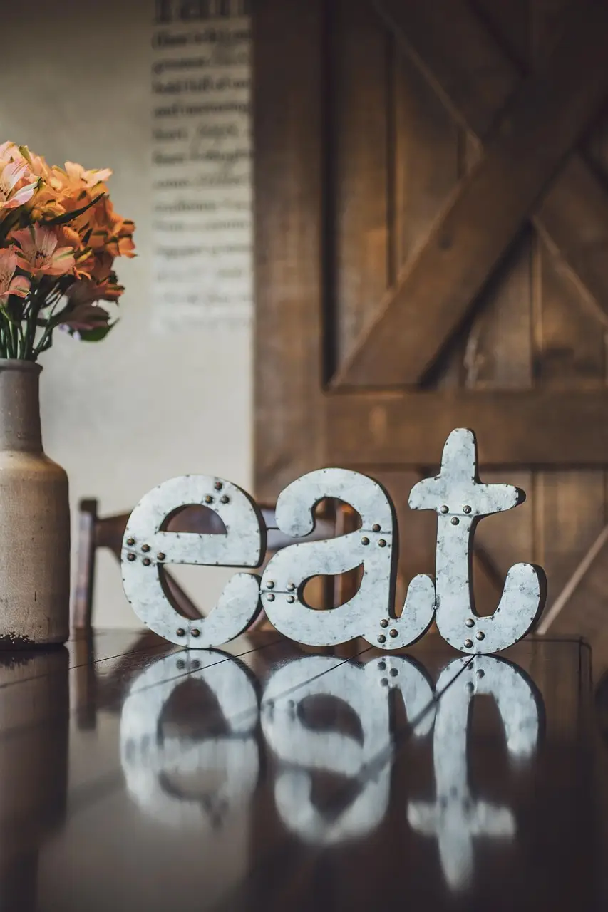 3 lettres en fer : e, a , t qui tiennent debout sur une table en bois. Le secret de notre relation à la nourriture en explorant les différents biais pour comprendre notre relation à la nourriture, dans le cadre d'une perte de poids