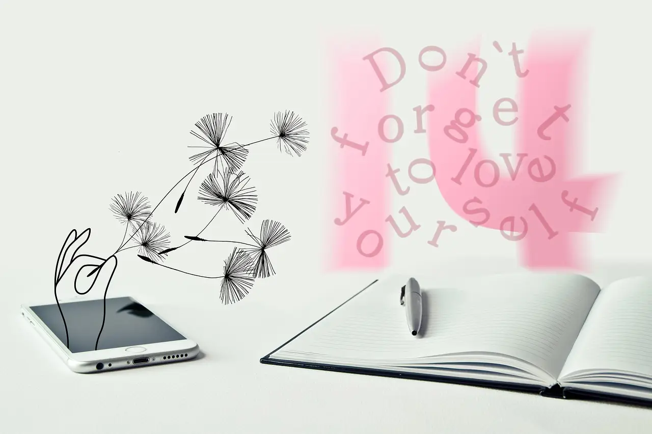 un. livre ouvert avec un stylo posé dessus, un téléphone portable est mis juste à côté du livre. Juste au dessus du livre, il y a des lettres rose qui flottent : don't forget to love yourself. Cultiver une reconnaissance interne pour une estime de soi solide.