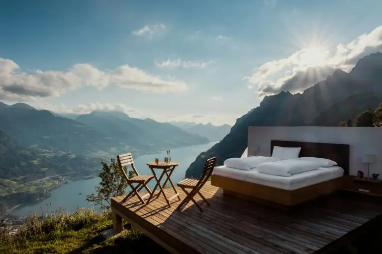 un lit posé sur une terrasse en bois, avec une table et 2 chaises en bois, installées au pied du lit, qui surplombe une falaise avec vue sur le fleuve. Sommeil et perte de poids : l'équation scrète pour mincir