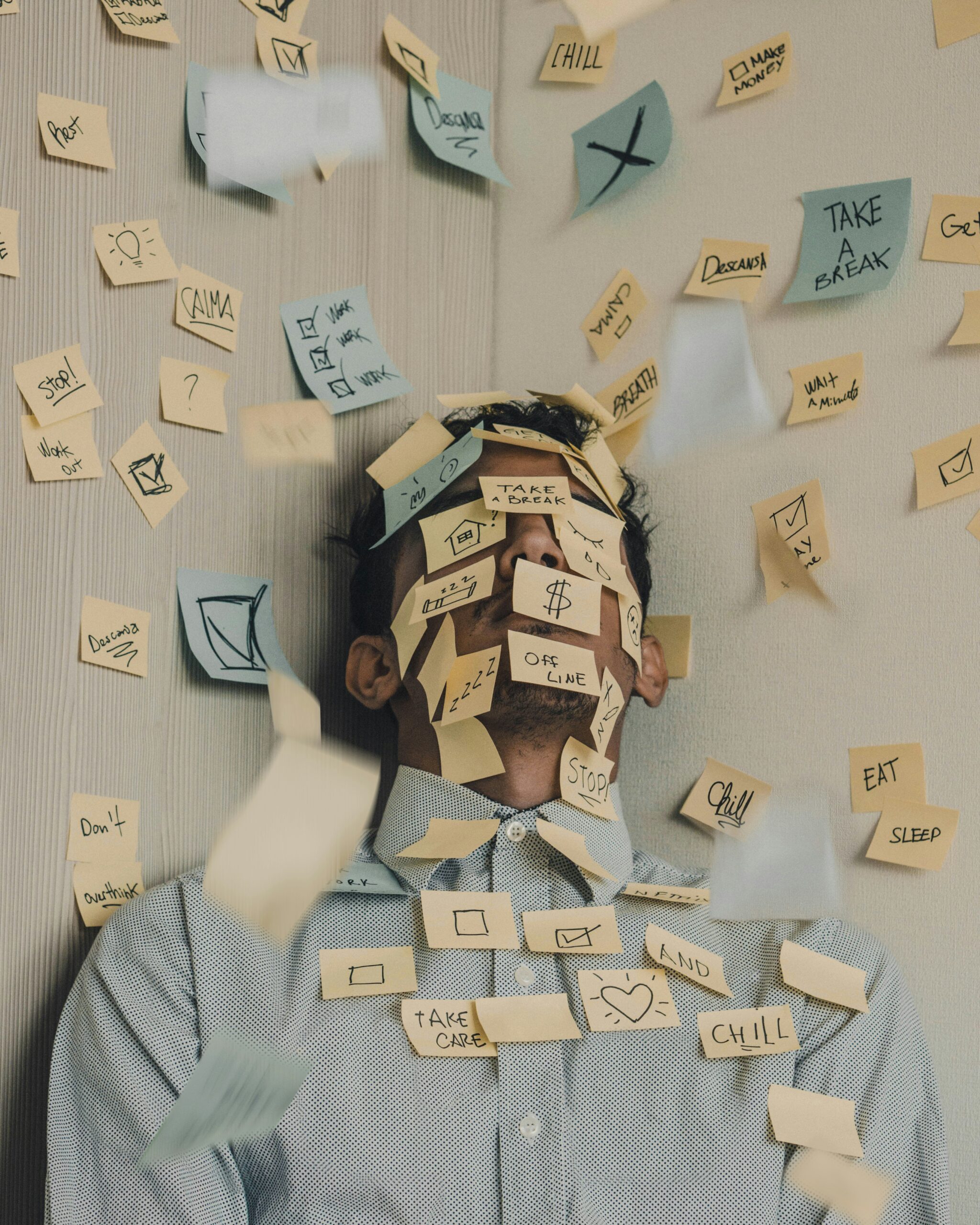 Homme allongé sur le sol, recouvert de post-it : hypnose et burn-out/stress au travail